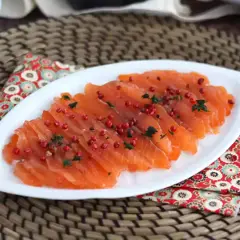 Pięknie pokrojony łosoś, idealny do gravlax przepis. Posypany różowym pieprzem i ziołami, prezentuje się apetycznie.