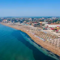 Widok na plażę z rzędami leżaków i parasoli. W tle zabudowania kurortowe. Woda w morzu czarnym jest ciepła, idealna do kąpieli.