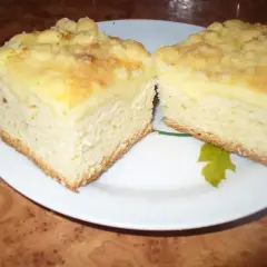 Dwa kawałki puszystego ciasta drożdżowego z kruszonką, podane na talerzu. Idealne na podwieczorek.