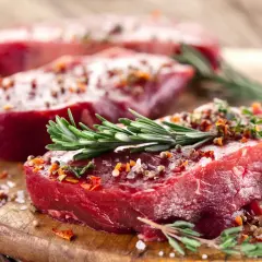 Trzy soczyste steki z żubra, doprawione ziołami i przyprawami, gotowe do grillowania.