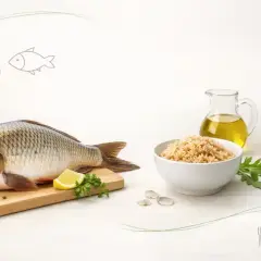 Świeży karp na desce z cytryną i ziołami, obok miska brązowego ryżu i dzbanek oliwy. Czy karp jest zdrowy? Tak, to doskonałe źródło białka i kwasów omega-3.
