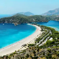 Widok na zatokę z turkusowym morzem, plażą i górami w tle. Bodrum zachwyca swoim morzem.