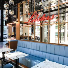 Elegancka restauracja z niebieskimi kanapami i neonem "Lobsters". Idealne miejsce na romantyczną kolację, które z pewnością znajdzie się w rankingu restauracji Warszawa.