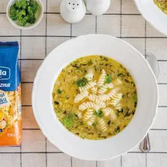 Aksamitna ogórkowa z makaronem świderki Lubella. Na stole obok talerza z zupą leży opakowanie makaronu.