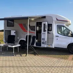 Gotowy kamperem nad morze. Rozłożony przedsionek, stolik i krzesła czekają na wypoczynek.