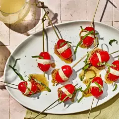 Kolorowe szaszłyki z pomidorkami koktajlowymi i mozzarellą, polane sosem. Idealne zdrowe przekąski na przyjęcie.