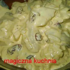 Kremowe śledzie w sosie curry z majonezem i rodzynkami, gotowe do podania.