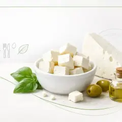 Czy ser feta jest zdrowy? Kostki sera feta w misce, oliwki, oliwa z oliwek i bazylia sugerują zdrową, śródziemnomorską dietę.
