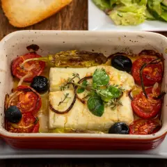Pyszna pieczona feta z pomidorkami, oliwkami i ziołami w ceramicznym naczyniu. Idealna na lekki posiłek.
