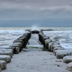 Kamienne pale wchodzące w morze bałtyckie, które jest częścią oceanu. Fale rozbijają się o brzeg.