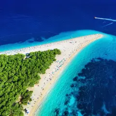 Widok z lotu ptaka na plażę w Chorwacji, gdzie turkusowe morze spotyka się z zielonym lasem sosnowym. Idealne miejsce na wakacje.