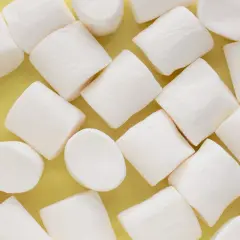 Białe, puszyste pianki marshmallow ułożone na żółtym tle. Pańska skórka, co to za słodka przyjemność!
