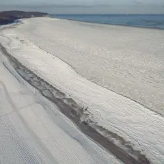 Zamarznięte Morze Bałtyckie, którego wiek jest trudny do określenia, pokryte lodem i śniegiem. W oddali widać statki.