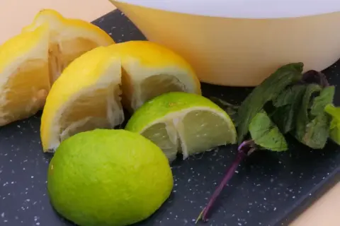 Kawałki cytryny i limonki, świeża mięta i miska. Idealne składniki na orzeźwiający napój.