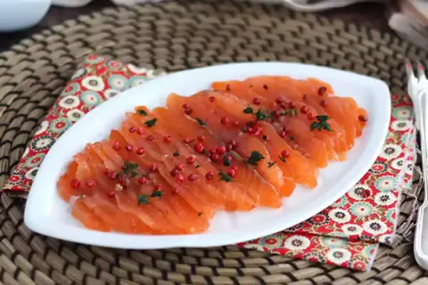 Pięknie pokrojony łosoś, idealny do gravlax przepis. Posypany różowym pieprzem i ziołami, prezentuje się apetycznie.