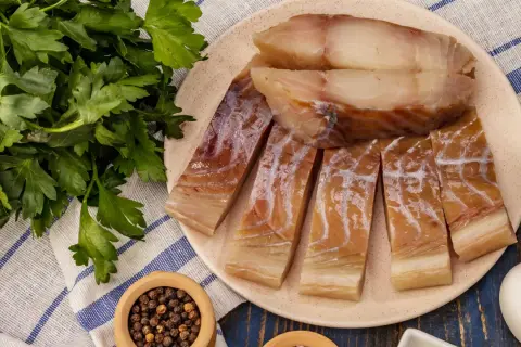 Pokrojona w plastry ryba czerniak, gotowa do podania z natką pietruszki i pieprzem.