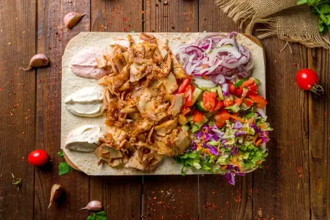 Pyszna baranina w kebabie z warzywami i sosami na desce.