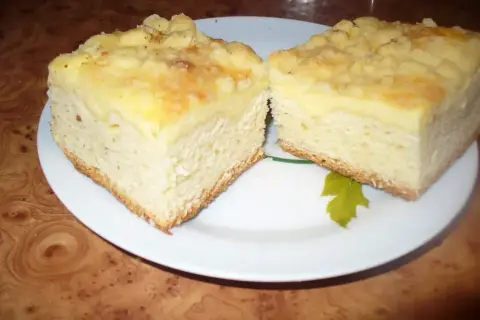 Dwa kawałki puszystego ciasta drożdżowego z kruszonką, podane na talerzu. Idealne na podwieczorek.