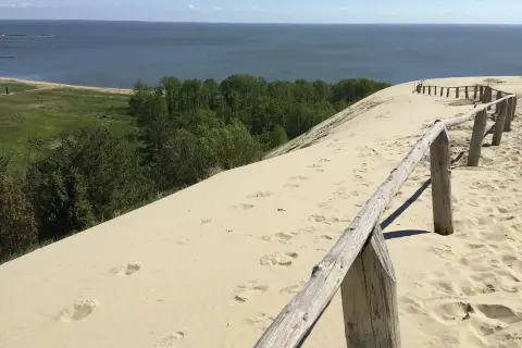 Piaskowe wydmy nad Bałtykiem, gdzie ślady stóp prowadzą do morza. Ciekawe, ile km ma morze bałtyckie, by dotrzeć do horyzontu?