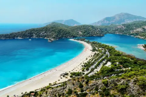 Widok na zatokę z turkusowym morzem, plażą i górami w tle. Bodrum zachwyca swoim morzem.