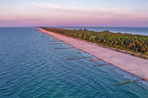 Zachód słońca nad Bałtykiem, gdzie widać piaszczystą plażę i las, tworzące najwęższe miejsce na Helu.