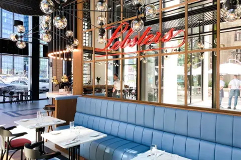 Elegancka restauracja z niebieskimi kanapami i neonem "Lobsters". Idealne miejsce na romantyczną kolację, które z pewnością znajdzie się w rankingu restauracji Warszawa.
