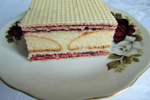 Pyszny andrut z kremem i dżemem, pokrojony na talerzyku z różami.