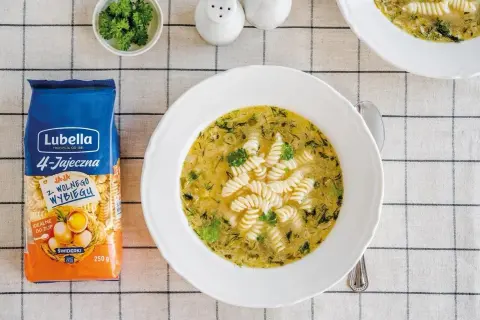 Aksamitna ogórkowa z makaronem świderki Lubella. Na stole obok talerza z zupą leży opakowanie makaronu.