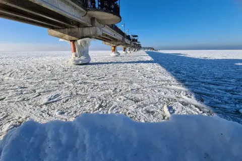 Molo na zamarzniętym morzu. Widać, czy morze zamarza, gdy lód pokrywa wodę i słupy molo.