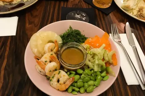 Kraków co zjeść? Kolorowa miska z krewetkami, ananasem, edamame i sosem. Idealna na lekki posiłek.