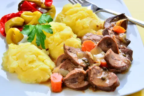 Cynaderki duszone z marchewką i cebulą, podane z puree ziemniaczanym i pikantnymi papryczkami. Pyszne danie, które warto spróbować!
