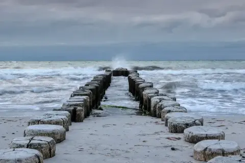 Kamienne pale wchodzące w morze bałtyckie, które jest częścią oceanu. Fale rozbijają się o brzeg.