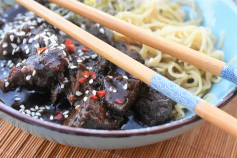 Pyszne żeberka po seczuańsku w sosie z sezamem i chili, podane z makaronem. Idealny przepis na obiad.