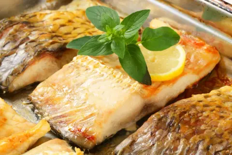 Pieczony karaś, złocisty i soczysty, z plasterkiem cytryny i gałązką ziół. Czy karaś jest smaczny? Ten wygląda apetycznie!
