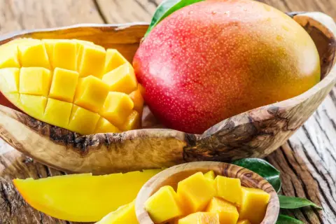 Soczysty mango owoc, pokrojony w kostkę i w całości, prezentuje swoje bogactwo witamin.