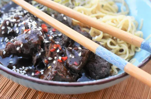 Pyszne żeberka po seczuańsku w sosie z sezamem i chili, podane z makaronem. Idealny przepis na obiad.