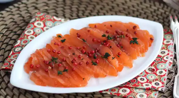 Pięknie pokrojony łosoś, idealny do gravlax przepis. Posypany różowym pieprzem i ziołami, prezentuje się apetycznie.