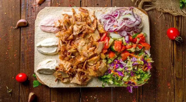 Pyszna baranina w kebabie z warzywami i sosami na desce.