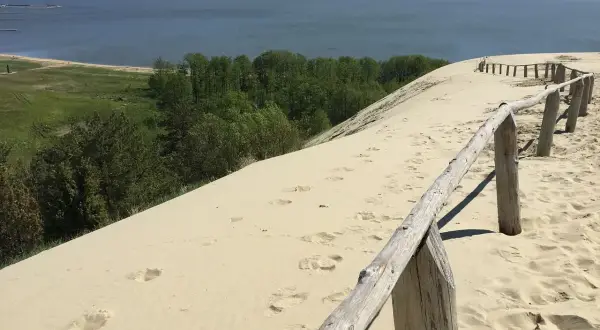 Piaskowe wydmy nad Bałtykiem, gdzie ślady stóp prowadzą do morza. Ciekawe, ile km ma morze bałtyckie, by dotrzeć do horyzontu?