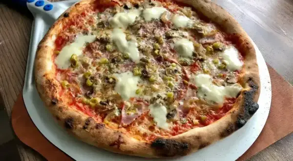 Pyszna pizza z grilla, z chrupiącym brzegiem, roztopionym serem i kolorowymi dodatkami, gotowa do podania.