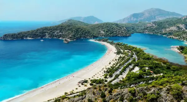 Widok na zatokę z turkusowym morzem, plażą i górami w tle. Bodrum zachwyca swoim morzem.