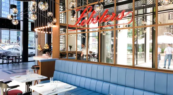 Elegancka restauracja z niebieskimi kanapami i neonem "Lobsters". Idealne miejsce na romantyczną kolację, które z pewnością znajdzie się w rankingu restauracji Warszawa.