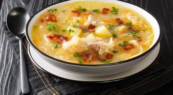 Gęsta zupa z kapusty kiszonej, ziemniaków i boczku, posypana natką pietruszki. Idealna na zimowe wieczory, smakuje jak u babci, prawdziwy pazibroda!