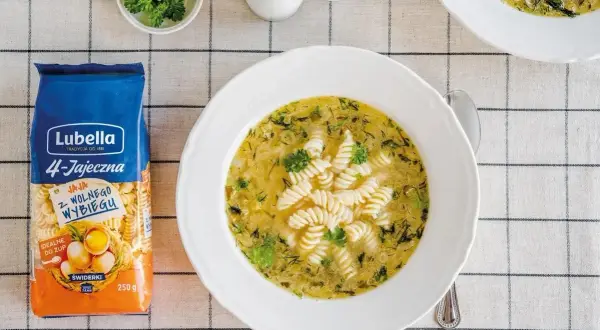 Aksamitna ogórkowa z makaronem świderki Lubella. Na stole obok talerza z zupą leży opakowanie makaronu.