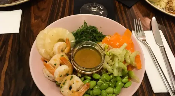 Kraków co zjeść? Kolorowa miska z krewetkami, ananasem, edamame i sosem. Idealna na lekki posiłek.