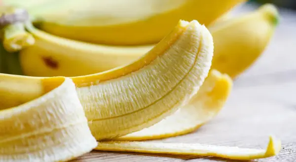 Banan, częściowo obrany, kusi swoim żółtym kolorem. Zastanawiasz się, ile potasu ma banan? Ten owoc to świetne źródło tego cennego minerału.