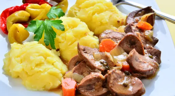 Cynaderki duszone z marchewką i cebulą, podane z puree ziemniaczanym i pikantnymi papryczkami. Pyszne danie, które warto spróbować!