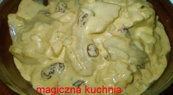 Kremowe śledzie w sosie curry z majonezem i rodzynkami, gotowe do podania.