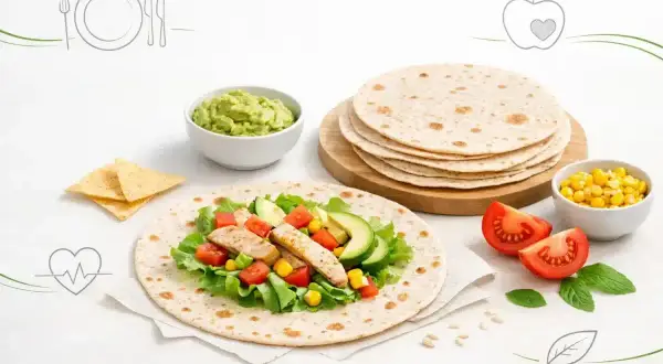 Czy tortilla jest zdrowa? Na talerzu pełnym świeżych warzyw, kurczaka i guacamole, stosik tortilli czeka na przygotowanie.