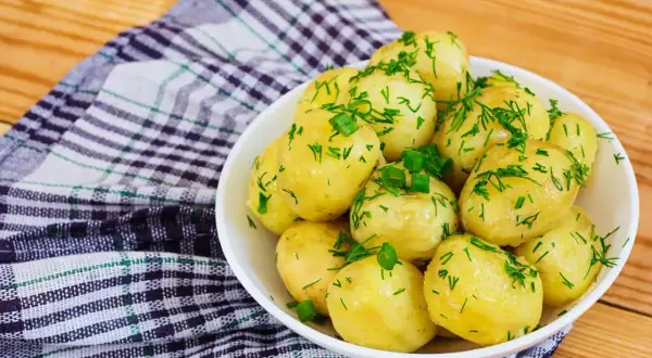Pyszne, młode ziemniaki posypane koperkiem i szczypiorkiem. Idealne, gdy zastanawiasz się, ile się gotuje ziemniaki.